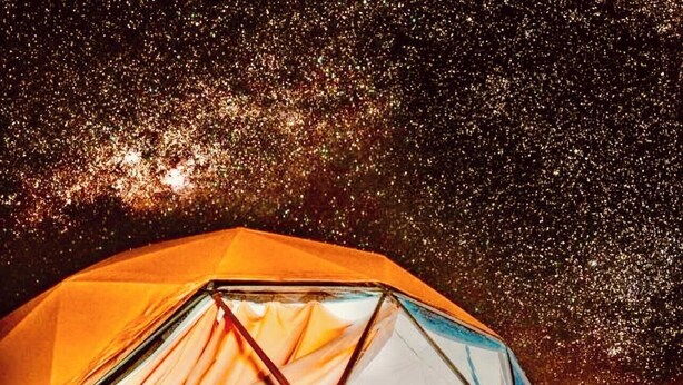 A tent with a clear interior, a person sitting inside, and a wooden floor. - Wadi Rum Main Road Visitor Center (Wadi Rum Village)