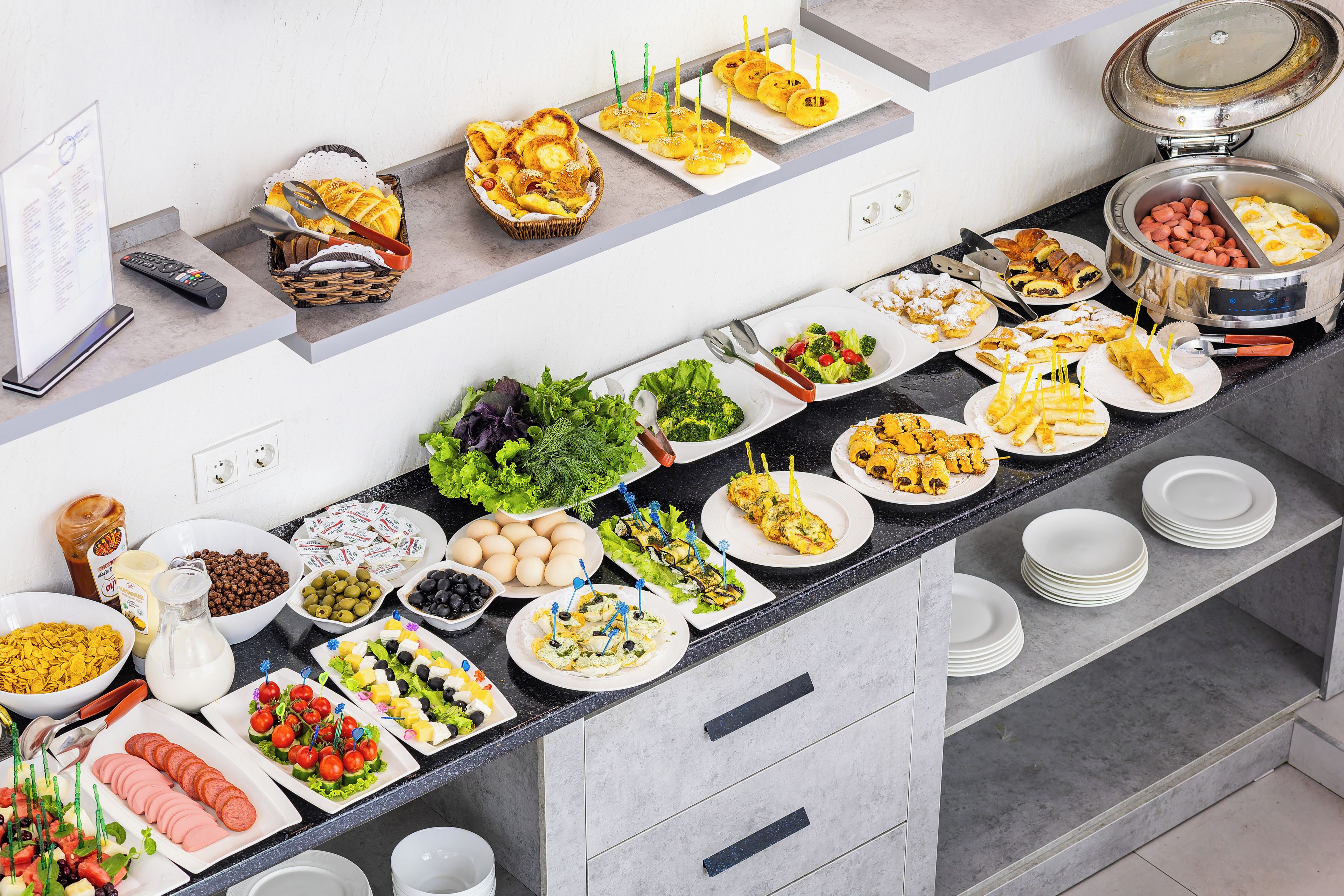 A buffet spread with various food items and utensils.