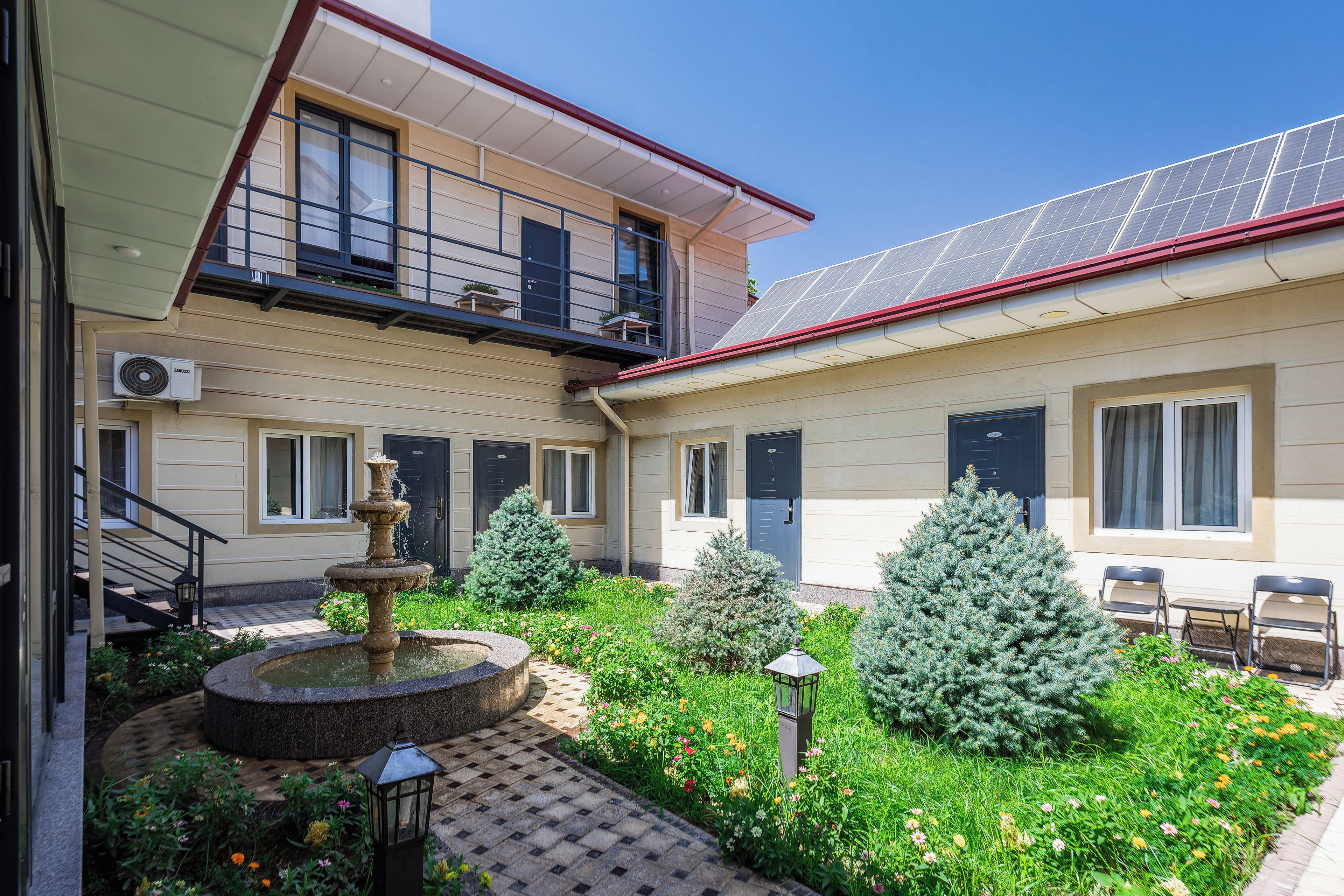 A courtyard with a fountain, potted plants, and a solar panel roof.