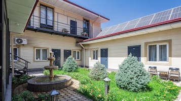 A courtyard with a fountain, potted plants, and a solar panel roof.