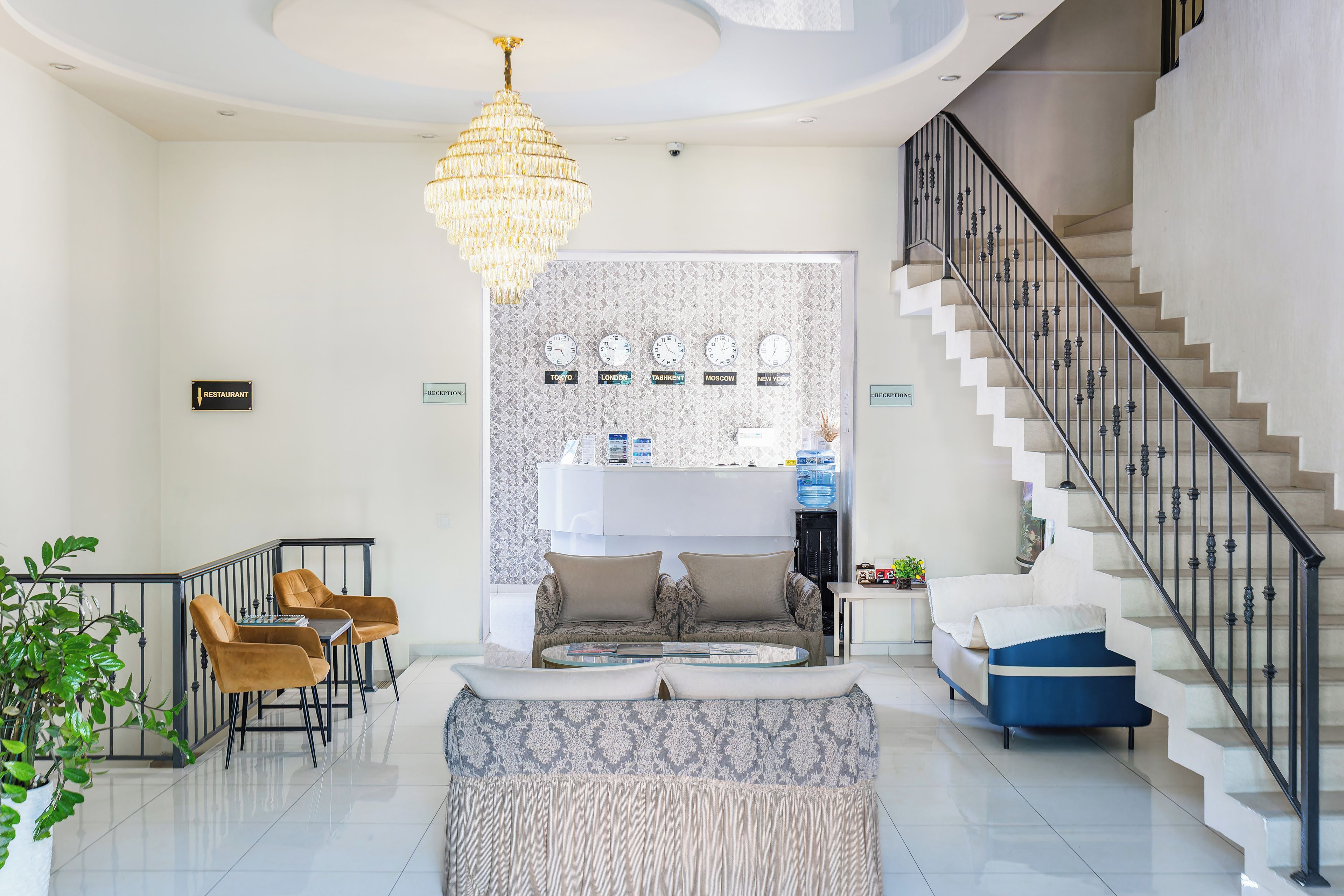 A spacious living area with a staircase, a chandelier, and a reception desk.