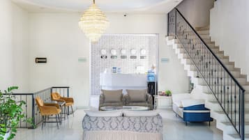 A spacious living area with a staircase, a chandelier, and a reception desk.