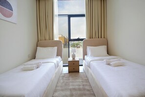 Ein Hotelzimmer mit zwei Betten, einem Nachttisch, einer Lampe und einem Fenster mit Vorhängen.