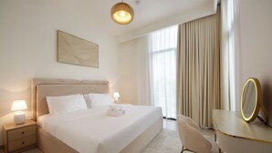 A hotel room with a large bed, bedside tables, a desk with a mirror, and a window with curtains. - Silk Valley - Luxury 3BR Villa near park (Dubai)