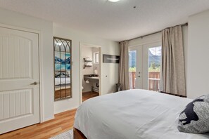 Ein Schlafzimmer mit einem großen Bett, ein Badezimmer mit Dusche und ein Balkon mit Blick.