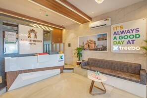 A szálloda recepciós területe, amelyben található egy recepciós pult, egy kanapé, egy kis asztal és egy a falra szerelt tábla.