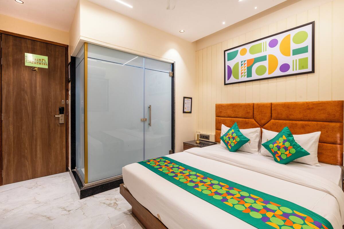 A hotel room with a bed, a wardrobe, and a wall-mounted artwork.