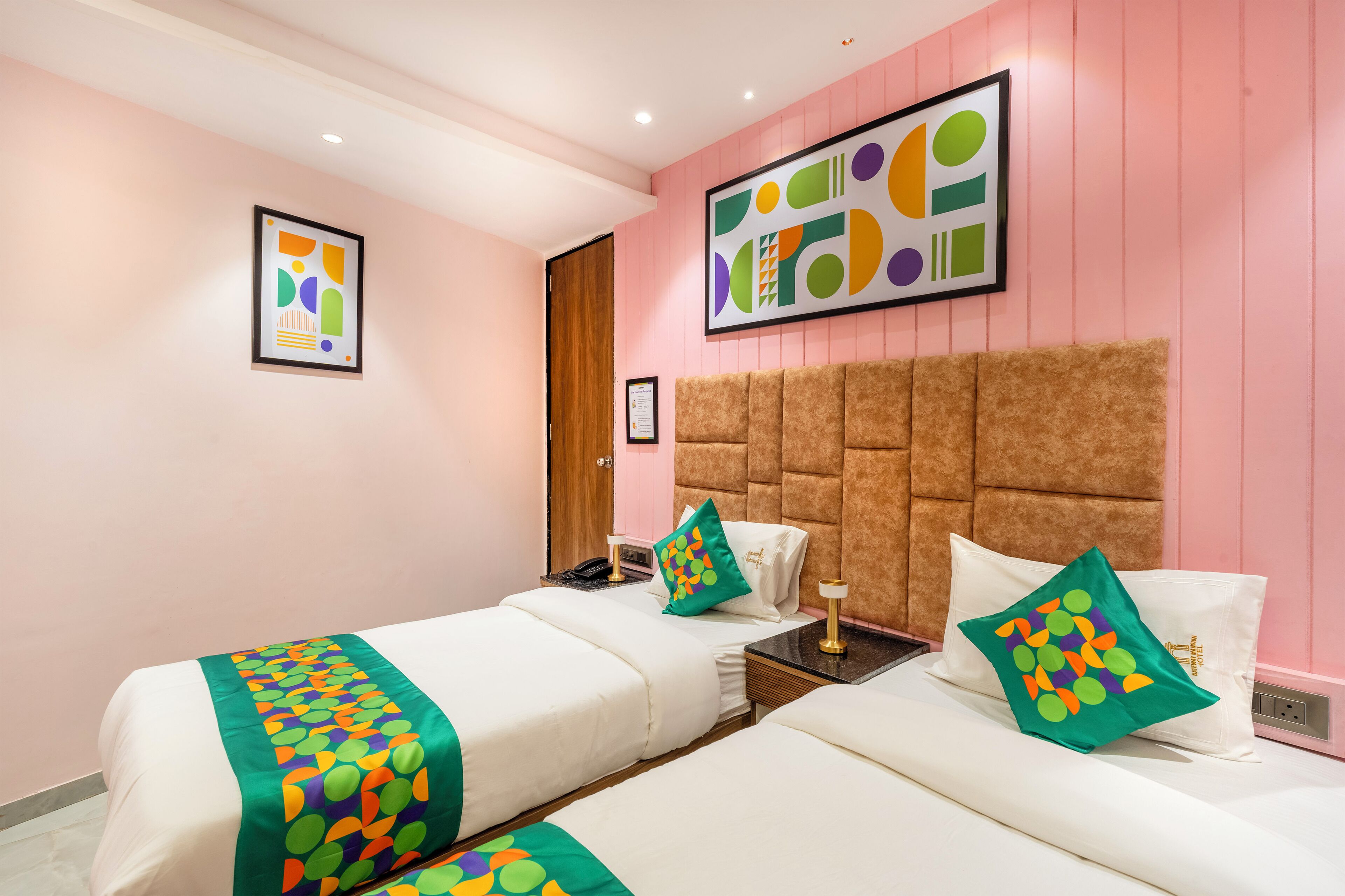 Une chambre d’hôtel avec deux lits, une grande peinture abstraite et une tête de lit en bois.