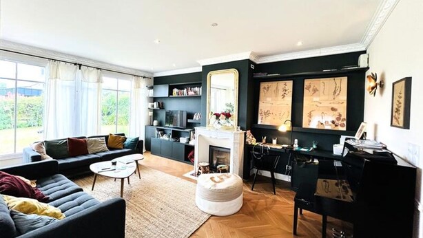 A modern living room with a sofa, coffee table, ottoman, fireplace, and artwork on the walls. - House in Larmor-plage Near Gr34 Trail (Larmor-Plage)