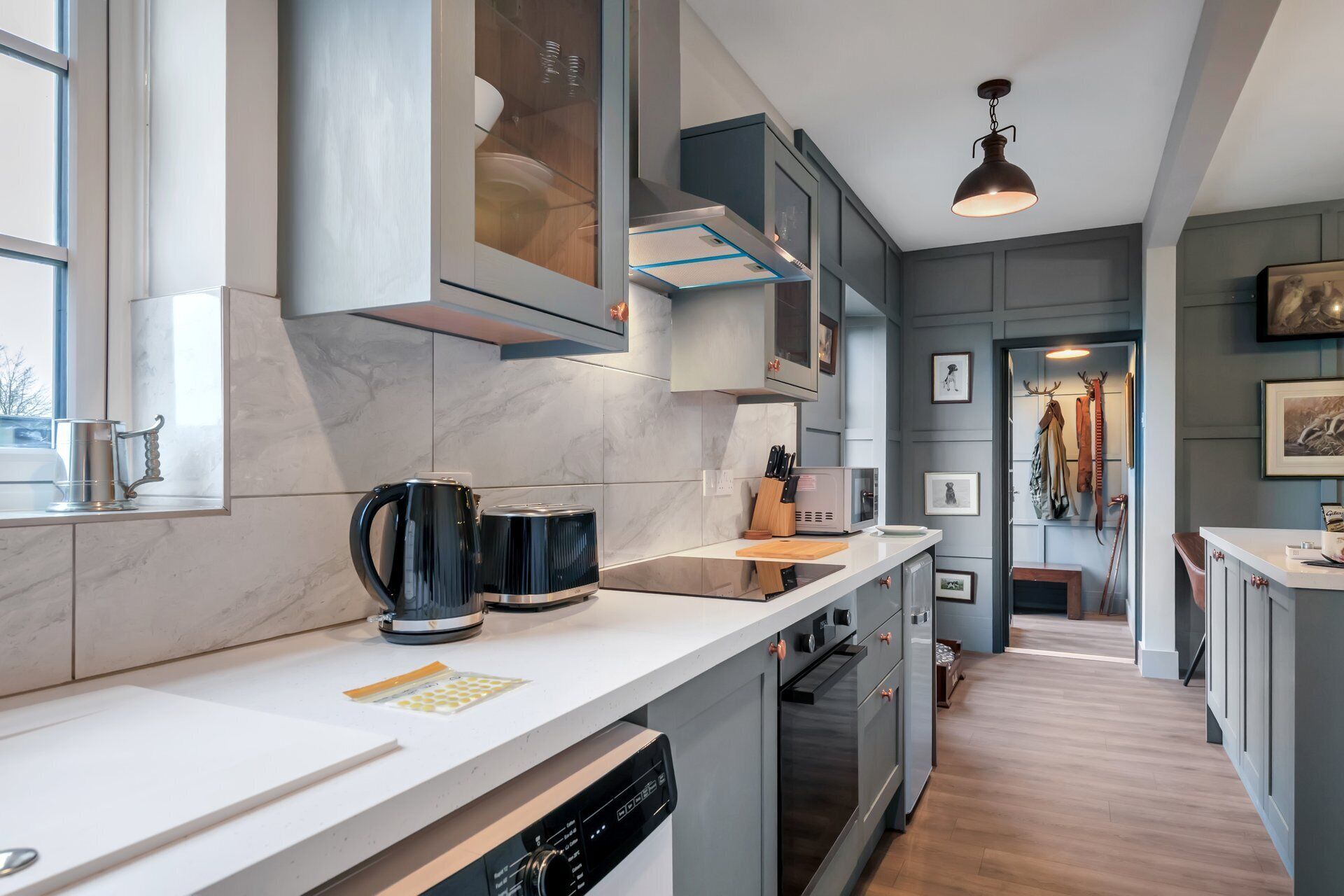 A modern kitchen with a white countertop, stainless steel appliances, and a view into the dining area.