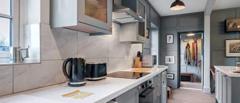 A modern kitchen with a white countertop, stainless steel appliances, and a view into the dining area.