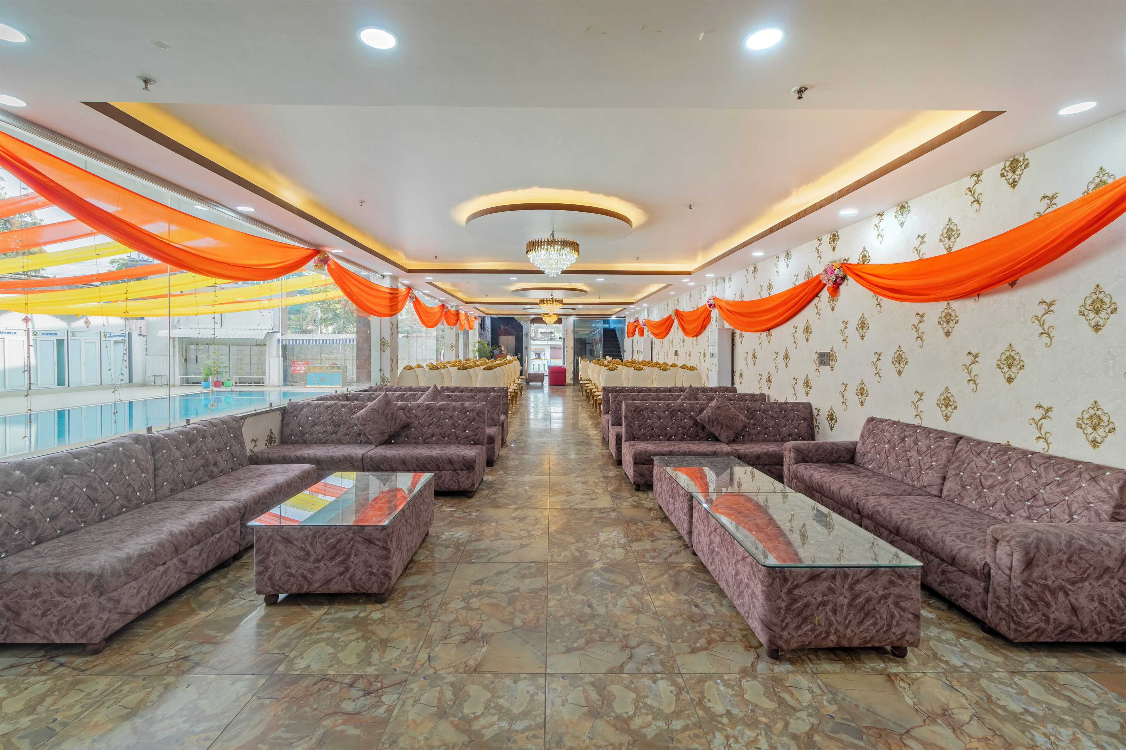 A spacious lobby with a pool view, featuring sofas and tables arranged in a central aisle.