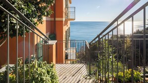 Een balkon met uitzicht op zee, een trap en plantenpotten.