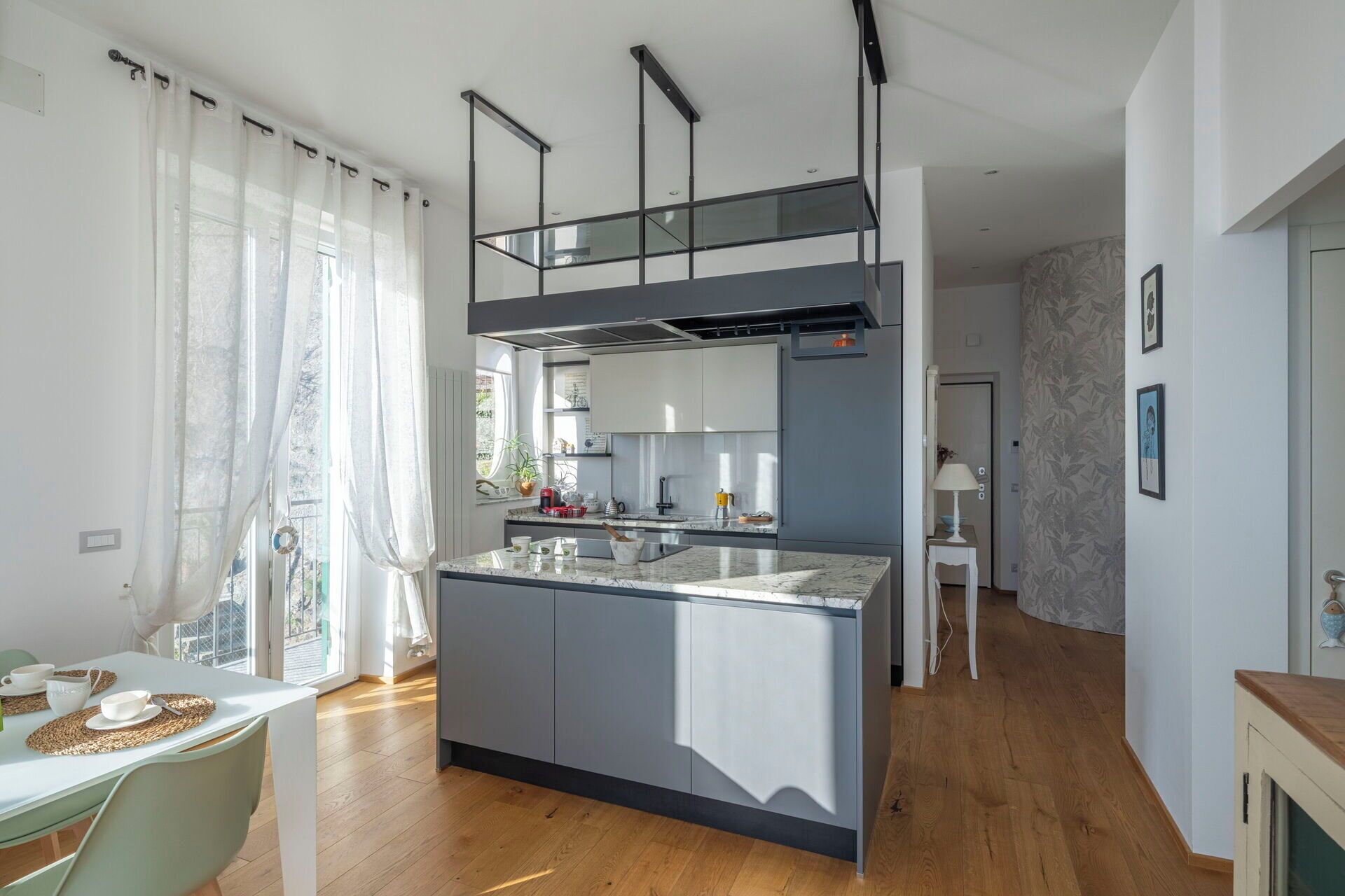 A modern kitchen with a central island, grey cabinetry, and a black ceiling structure.