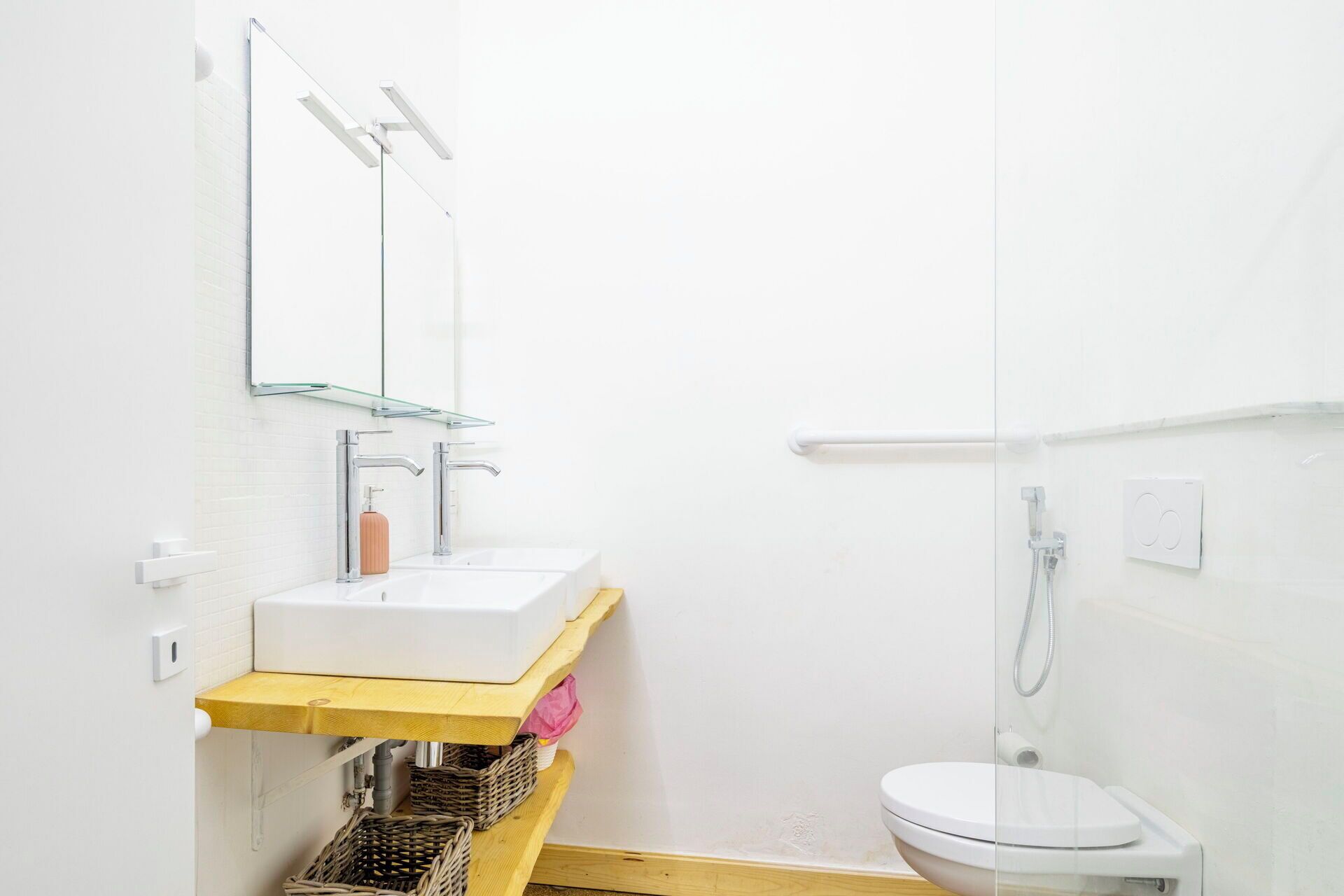 Un bagno piccolo e moderno con lavandino, specchio e water bianchi.