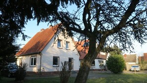 Ein zweistöckiges Haus mit rotem Ziegeldach, weißen Wänden und einem kleinen Vorgarten.