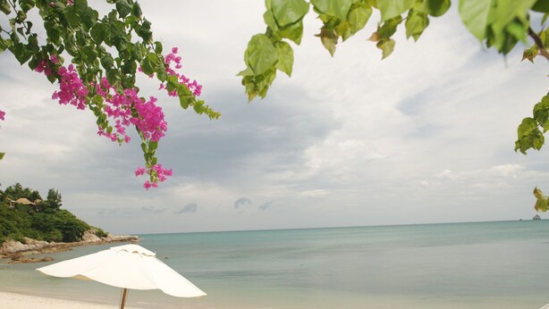 A beach with a white umbrella and two wooden lounge chairs. - Villa mit Blick auf das Wasser by Interhome (Koh Samui)
