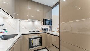 A modern kitchen with a built-in oven, microwave, and stainless steel appliances. - Community View 1BR, Perfectly Located Near the Park, Adhara Star, Arjan (Dubai)
