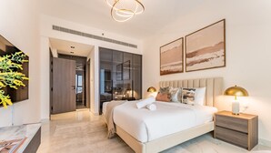 A modern bedroom with a large bed, bedside tables, a TV, and artwork on the wall. - Community View 1BR, Perfectly Located Near the Park, Adhara Star, Arjan (Dubai)
