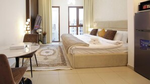 Una camera d'albergo con un letto, un tavolo da pranzo, una sedia, un frigorifero e vista sull'esterno.
