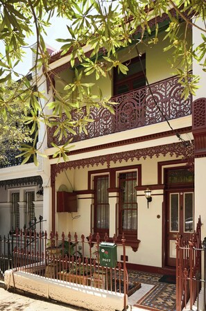 A two-story building with ornate balconies, a traditional design, and a small garden area. - Four-Bedroom Heritage Terrace in Paddington (Paddington)