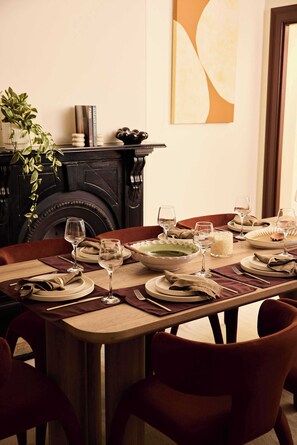 A dining table set for four with wine glasses, plates, and a centerpiece. - Four-Bedroom Heritage Terrace in Paddington (Paddington)