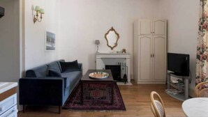 A living room with a sofa, a coffee table, a fireplace, a television, and a wardrobe. - Stay at the Château- Studio 2P- with pool and park (Fajolles)