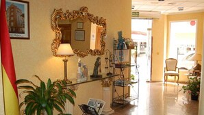 A lobby with a large ornate mirror, a statue, a glass display case, and a reception desk.