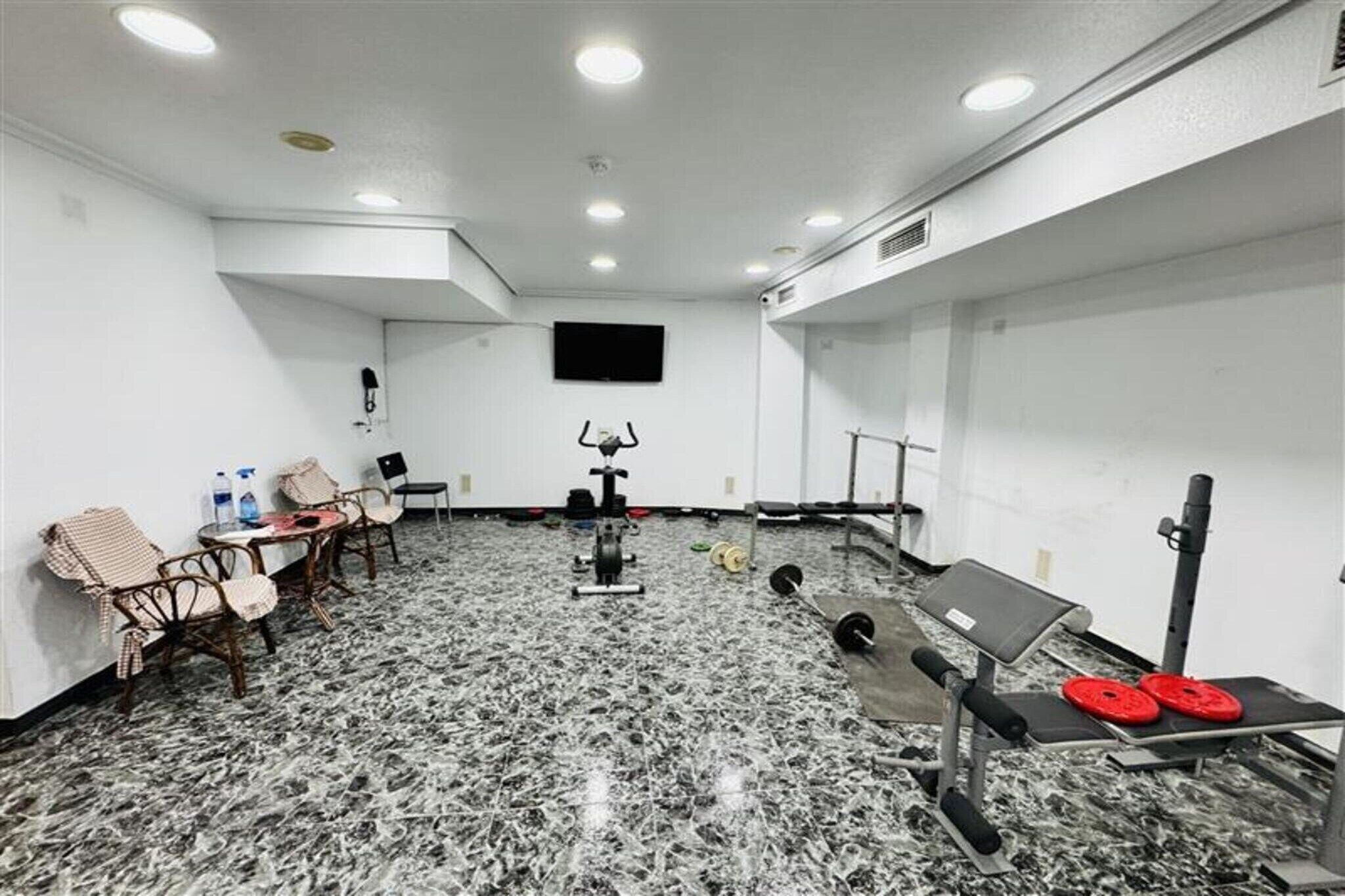 Une salle de sport équipée de matériel d’exercice, d’un téléviseur et de coins salon.