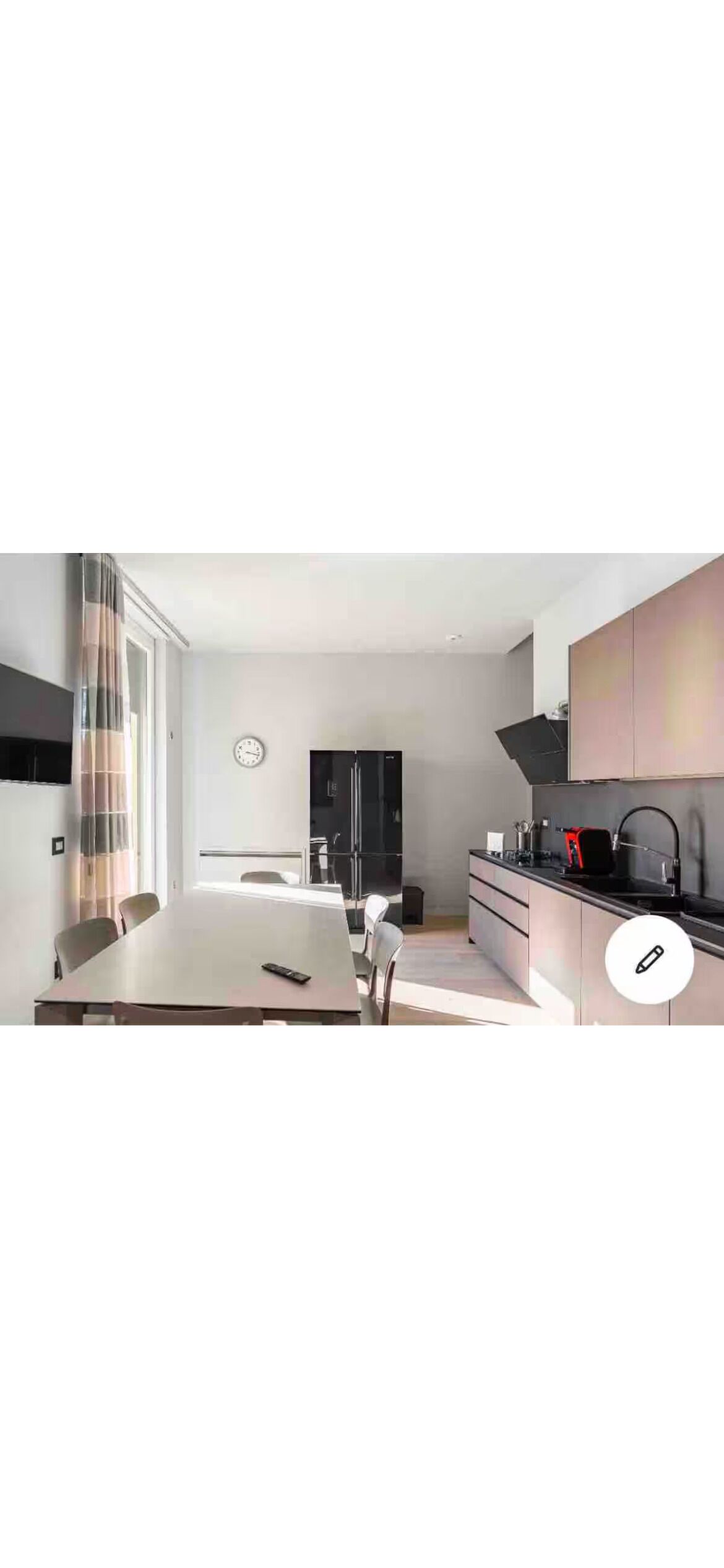 A modern kitchen with a dining table, chairs, and a clock on the wall.