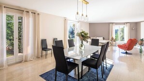 A modern dining area with a glass table, black chairs, and a vase of flowers. - Quiet House with Pool (Biot)