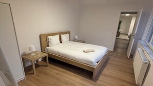 Une chambre à coucher avec un lit en bois, une table de chevet et une petite table d’appoint.
