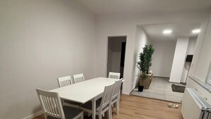 Une pièce spacieuse avec une grande table à manger et des chaises, une plante en pot et un radiateur.
