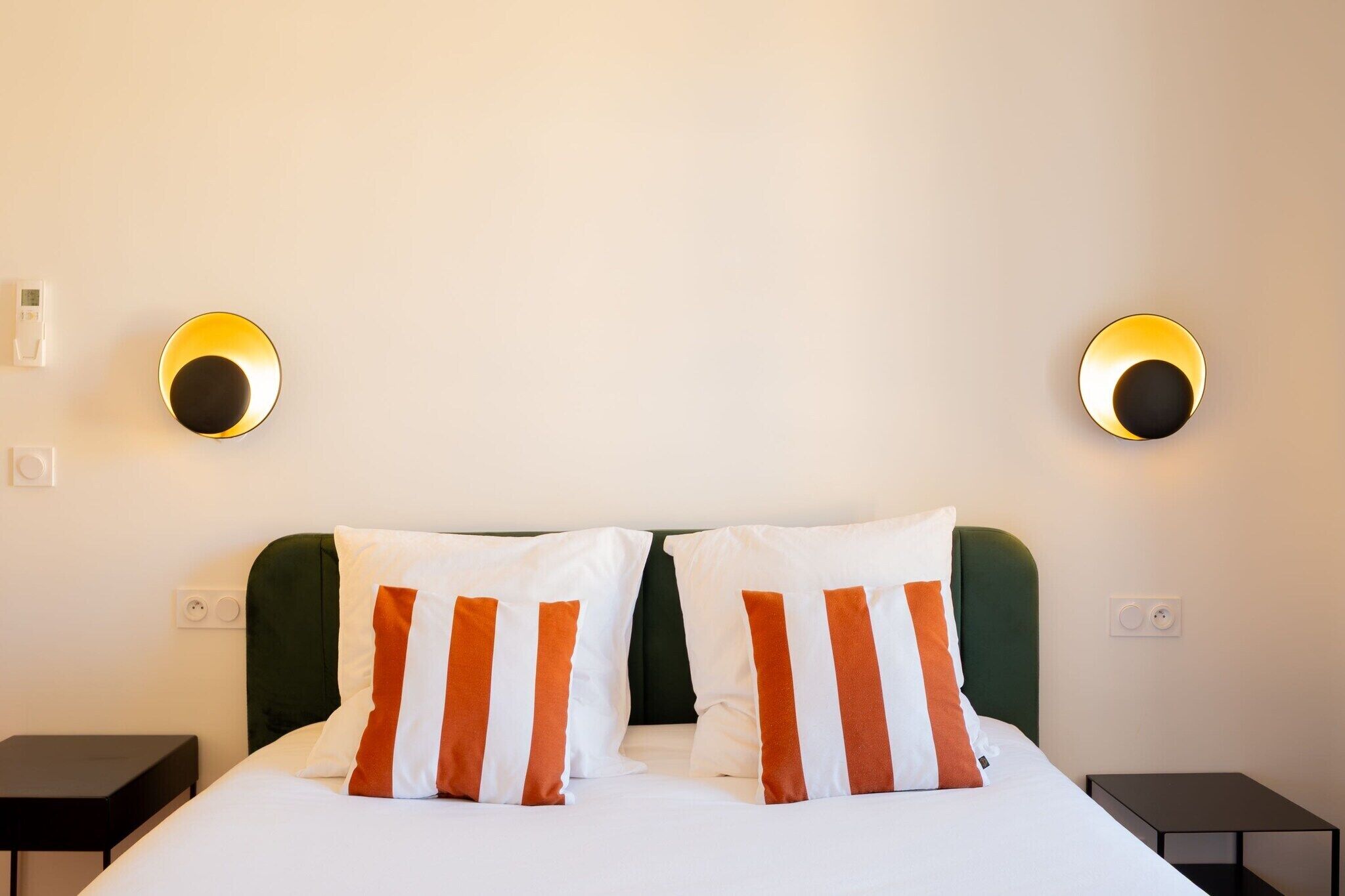Una camera d'albergo con un letto, due comodini e lampade a parete.