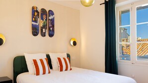 Ein Bett mit weißer Bettwäsche und gestreiften Kissen, ein grüner Kopfteil und eine Wand mit drei Skateboards.