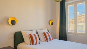 A bed with white and orange striped pillows, a green headboard, and two wall-mounted lights. - Saint-Tropez: Bright apartment near the port (Saint-Tropez)