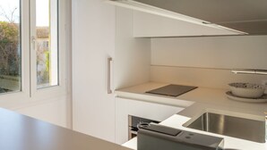 A modern kitchen with a built-in oven, a stainless steel sink, and a window overlooking a garden. - Saint-Tropez: Bright apartment near the port (Saint-Tropez)