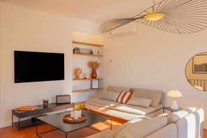 Una sala de estar moderna con televisor de pantalla plana, un sofá, una mesa de centro y una lámpara de techo original.