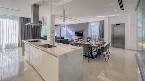 Een moderne keuken met een marmeren eiland, een eethoek met stoelen en een aan de muur bevestigde televisie.