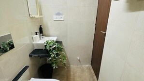 Un bagno piccolo con il water, un lavandino, uno specchio e una pianta in vaso.