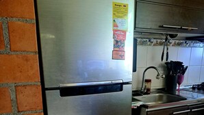 Ein Edelstahl-Kühlschrank in einer Küche mit Fliesenrückwand und Backsteinwand.