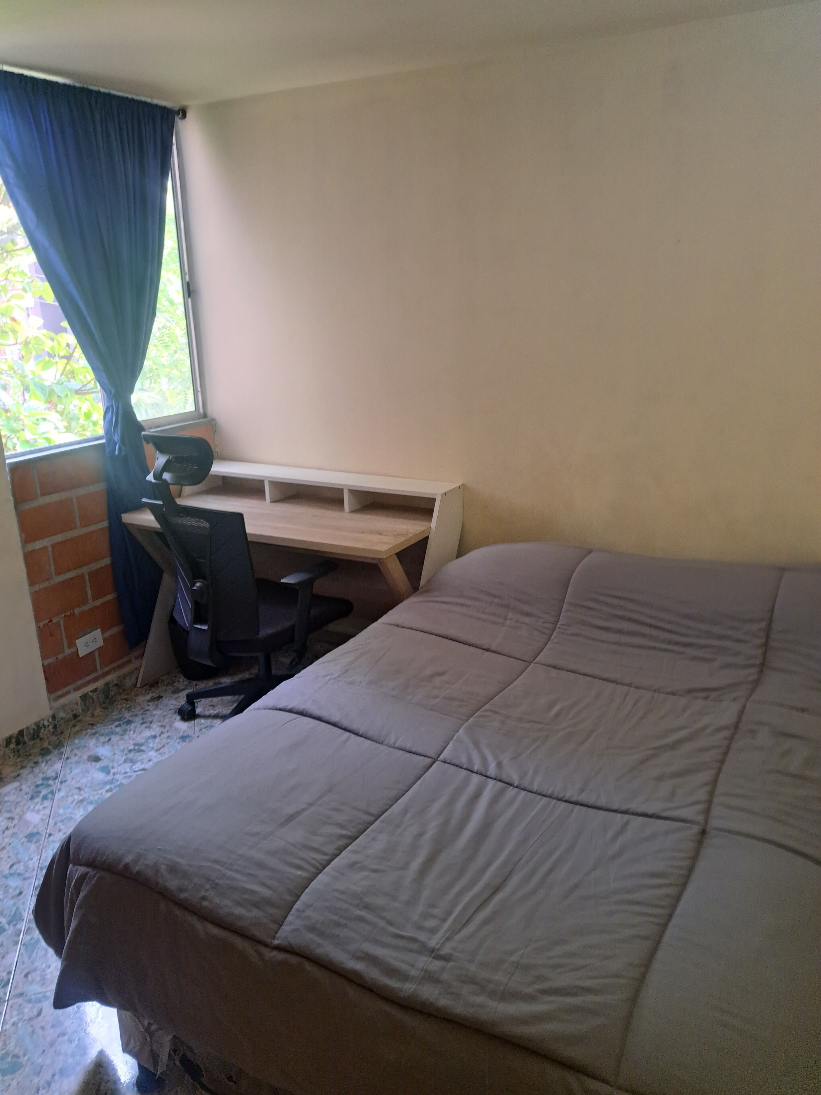 A bedroom with a bed, a desk, and a chair.
