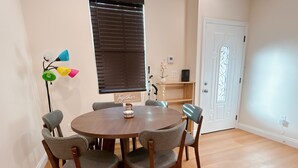 A dining area with a round wooden table surrounded by six grey upholstered chairs. - Lovely 3-bedroom house with AC in charming San Gabriel (San Gabriel)