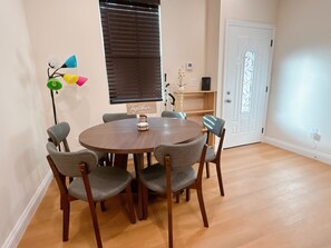 Un comedor con una mesa redonda de madera rodeada por seis sillas tapizadas de color gris.