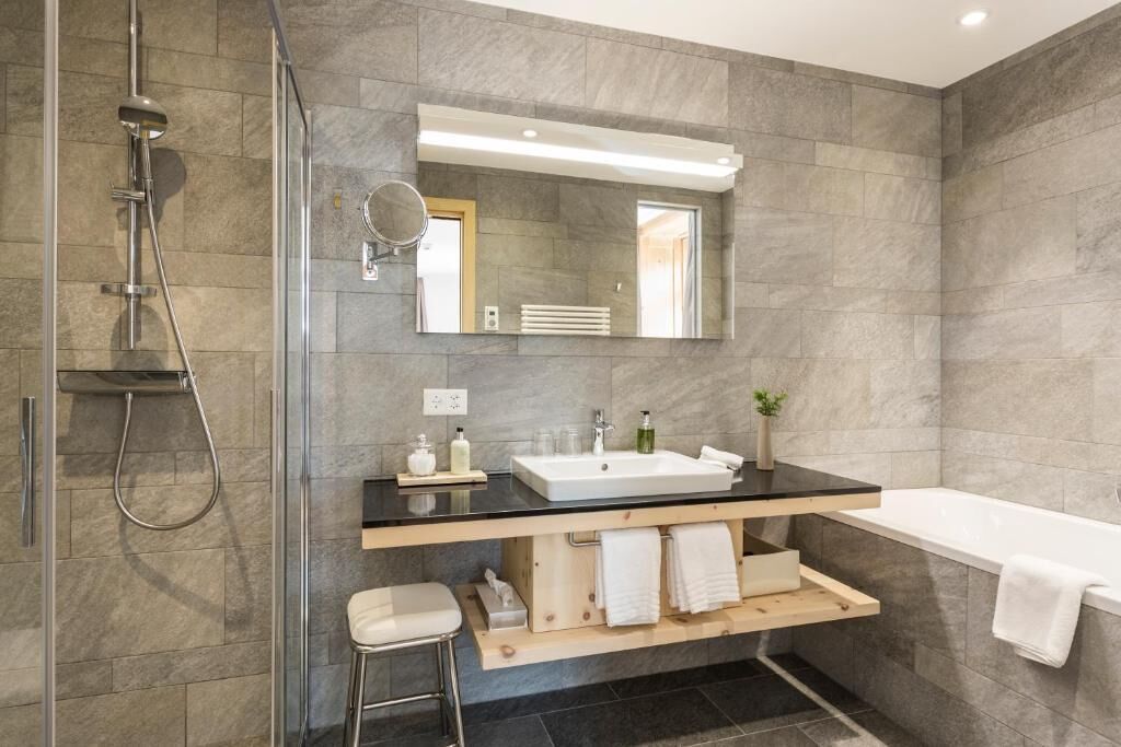 A modern bathroom with a glass-enclosed shower, a large mirror, a white sink, and a bathtub.