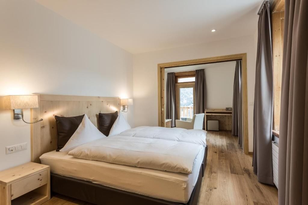 Een hotelkamer met een groot bed, nachtkastje, bureau en stoel.