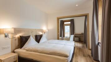 Een hotelkamer met een groot bed, nachtkastje, bureau en stoel.