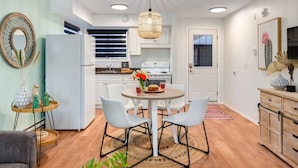 Una cocina moderna con armarios blancos, una mesa de comedor redonda y una lámpara colgante.