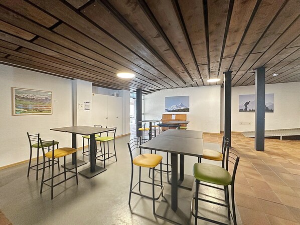 A modern interior with tables and chairs, wooden beams on the ceiling, and artwork on the walls. - Alpine Club Retreat - Central Studio, Pool & View (Crans-Montana)