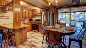 Una cocina amplia con armarios de madera, un refrigerador de acero inoxidable y un comedor con una mesa grande y sillas.